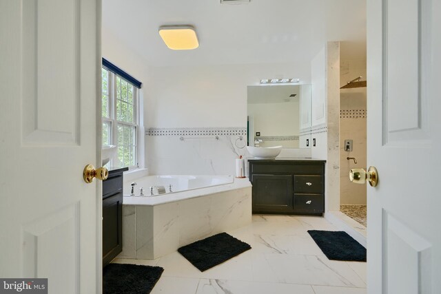 bathroom with a shower stall, vanity, a bath, and marble finish floors