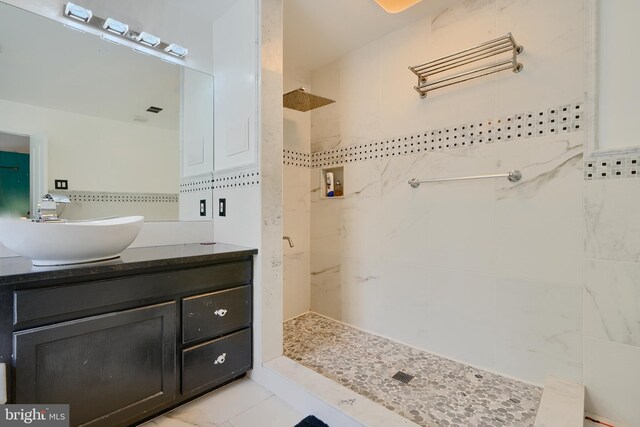 full bathroom with tiled shower and vanity