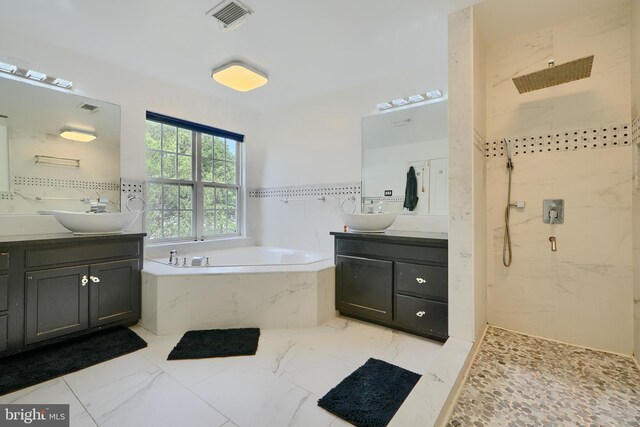 full bathroom with a marble finish shower, a bath, two vanities, and marble finish flooring