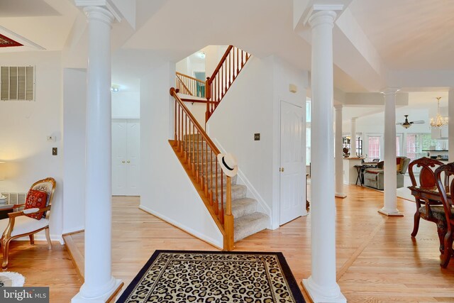 stairs with ornate columns, wood finished floors, and baseboards