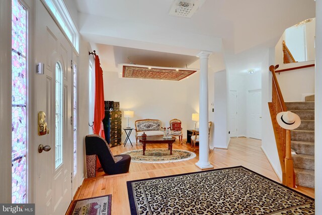 foyer entrance featuring stairs, wood finished floors, and ornate columns