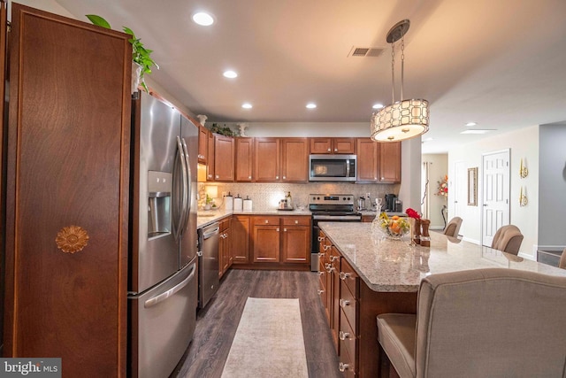 250 Parkside Ct, Woodstock, VA 22664 - kitchen with stainless steel appliances, dark wood-style floors, a breakfast bar, brown cabinets, and light stone countertops
