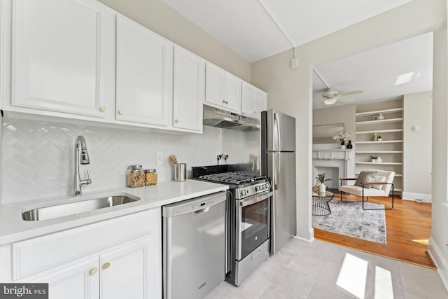 1527 Park Rd NW Unit 302, Washington, DC 20010 - kitchen with appliances with stainless steel finishes, a sink, under cabinet range hood, white cabinets, and decorative backsplash