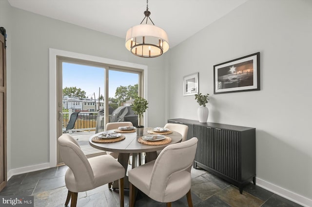 dining space featuring baseboards, stone tile flooring, and a chandelier