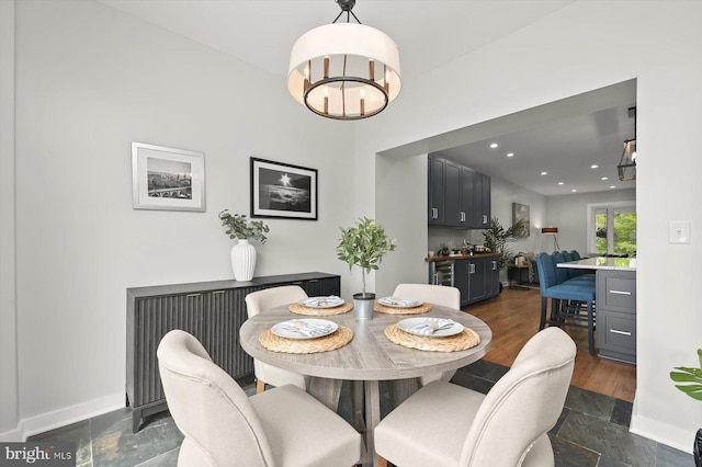 dining area with a chandelier, stone tile floors, baseboards, and recessed lighting