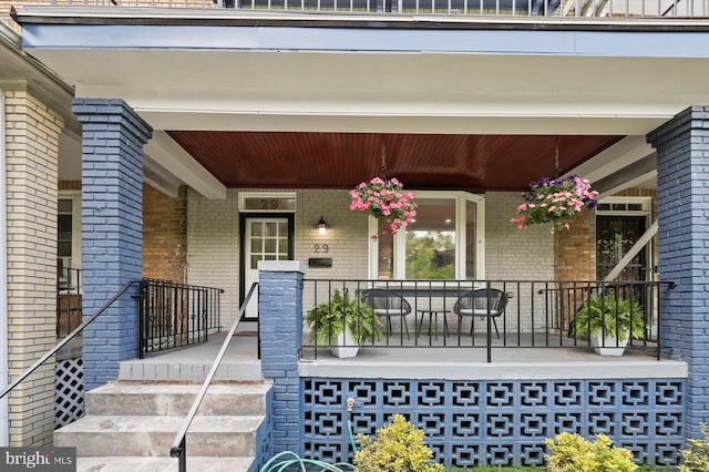 property entrance featuring covered porch and brick siding