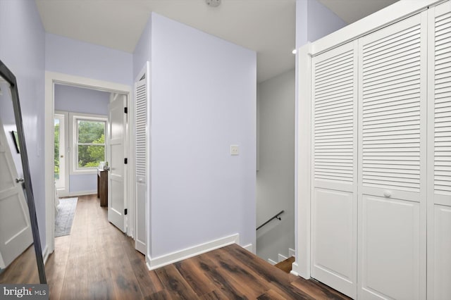 hallway with an upstairs landing, wood finished floors, and baseboards