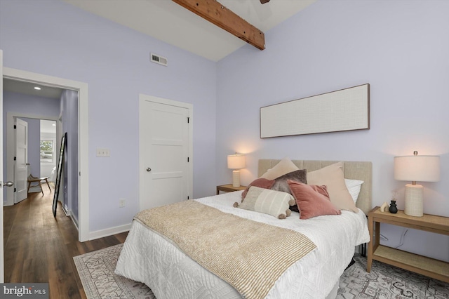bedroom featuring beam ceiling, wood finished floors, and baseboards