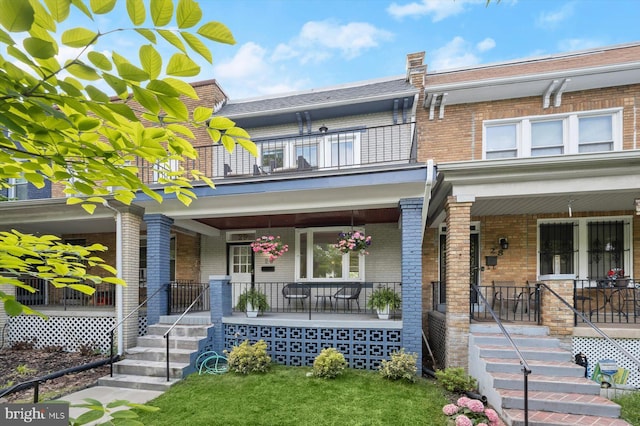 townhome / multi-family property featuring a porch, brick siding, and a balcony