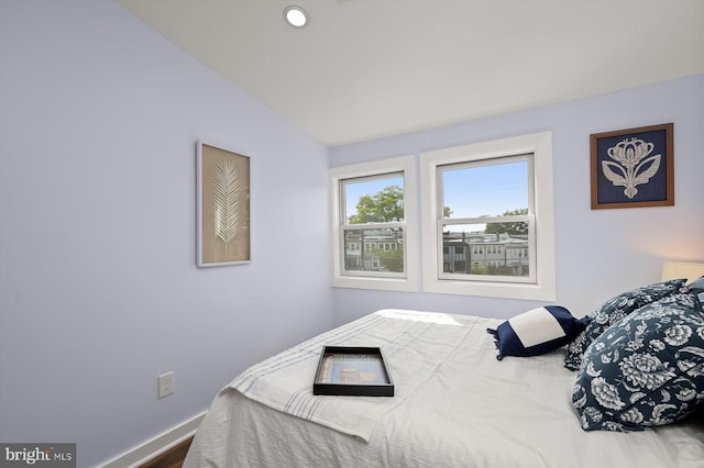 bedroom with lofted ceiling and baseboards