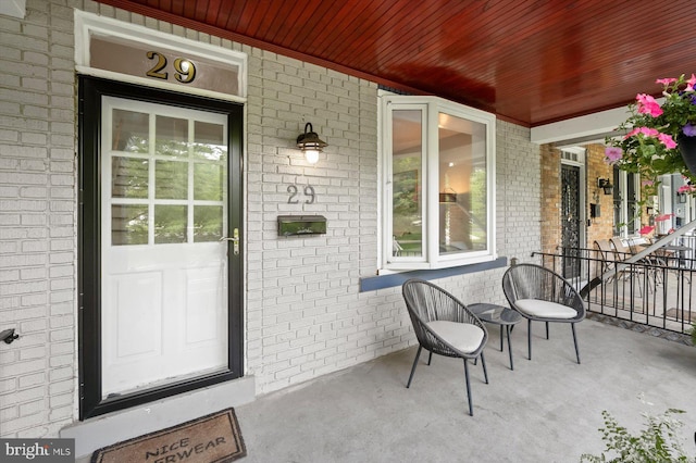 entrance to property with a porch and brick siding