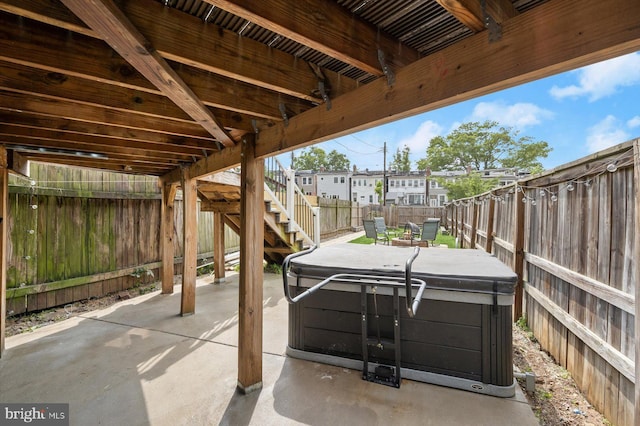 fenced backyard with a hot tub, a patio, and stairway