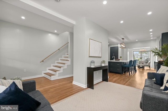 living room featuring light wood-style floors, recessed lighting, stairs, and baseboards