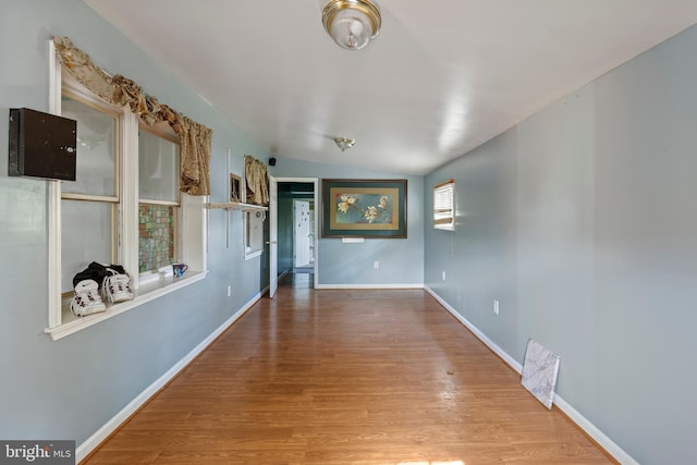 hallway with baseboards, wood finished floors, and lofted ceiling