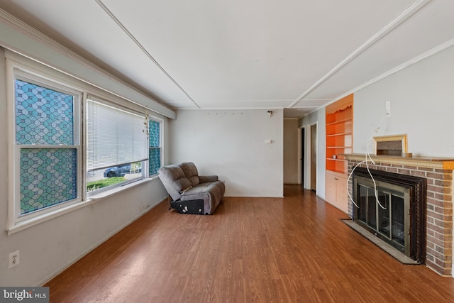 unfurnished room featuring baseboards, built in features, wood finished floors, and a fireplace