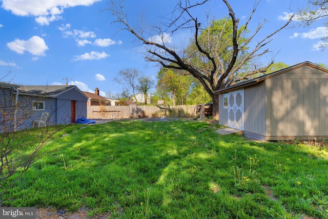 view of yard featuring an outdoor structure, a fenced backyard, and a storage unit