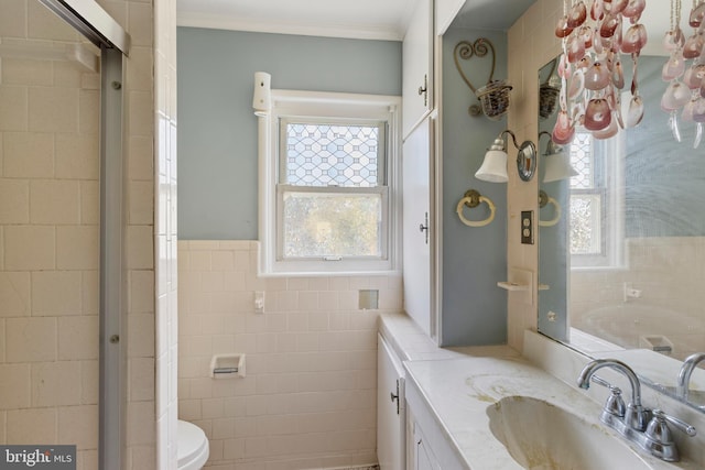 full bathroom with plenty of natural light, ornamental molding, vanity, and tile walls