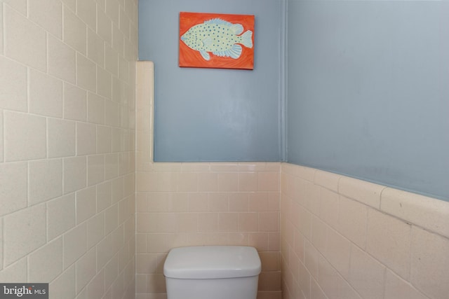 bathroom featuring toilet and tile walls