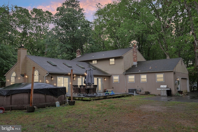 595 Tabernacle Rd, Medford, NJ 08055 - back of property at dusk featuring a garage, a deck, central AC, and view of wooded area