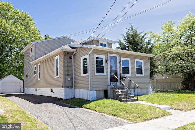 view of front of property featuring a front yard, a garage, fence, an outdoor structure, and aphalt driveway
