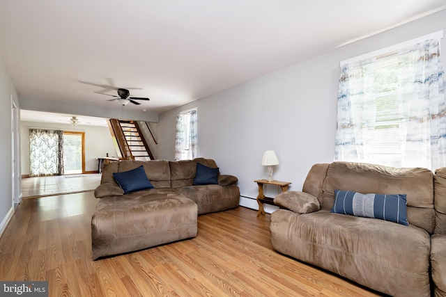 living room featuring baseboards, a ceiling fan, wood finished floors, and stairway