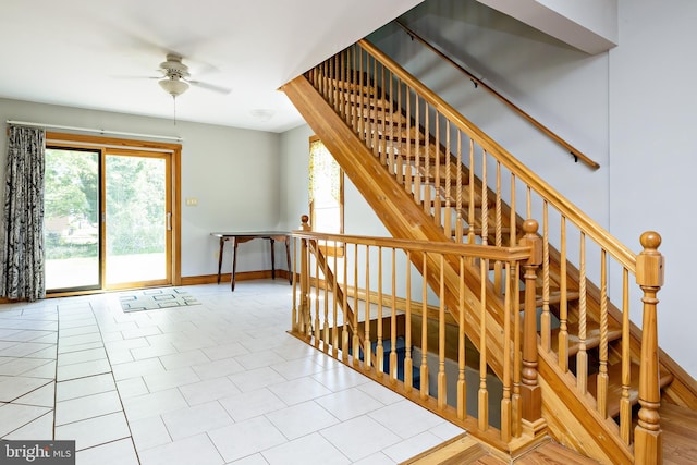 stairway with a ceiling fan, baseboards, plenty of natural light, and tile patterned flooring