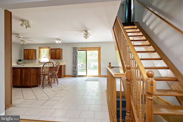 kitchen featuring light countertops, brown cabinets, ceiling fan, and baseboards