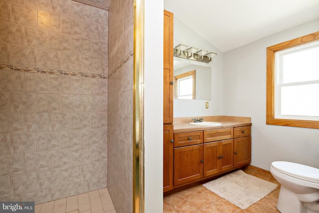 full bathroom featuring vanity, toilet, tile patterned floors, lofted ceiling, and a stall shower