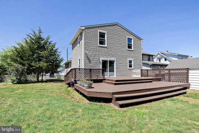 back of property featuring a lawn, a deck, and fence