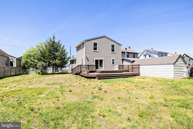 back of property with fence, an outdoor structure, a yard, and a deck