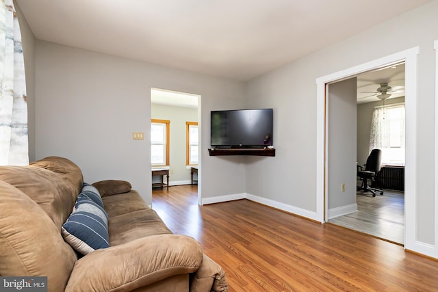 living room with baseboards, a ceiling fan, and wood finished floors