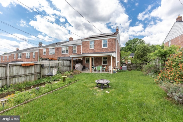 263 Medwick Garth E, Baltimore, MD 21228 - back of property with an outdoor fire pit, a chimney, a patio area, brick siding, and solar panels
