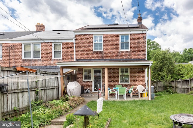 263 Medwick Garth E, Baltimore, MD 21228 - rear view of property with brick siding, a chimney, solar panels, and a patio