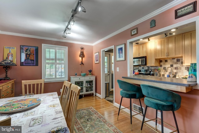 263 Medwick Garth E, Baltimore, MD 21228 - kitchen featuring track lighting, light brown cabinets, a kitchen bar, light wood-style flooring, and backsplash
