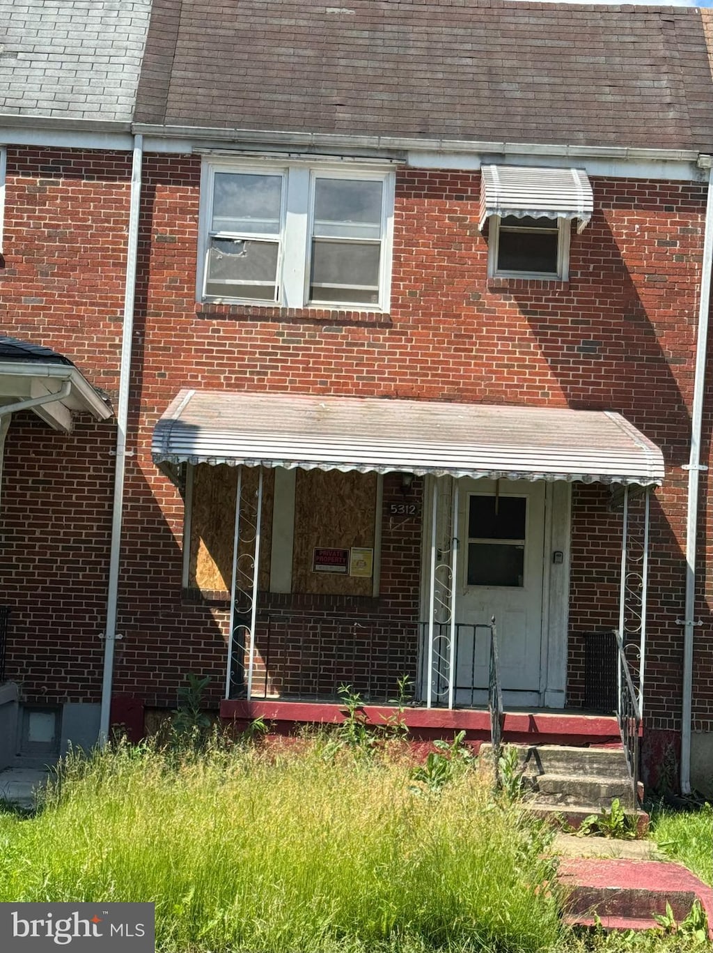 5312 Gist Ave, Baltimore, MD 21215 - townhome / multi-family property with roof with shingles, brick siding, and a porch