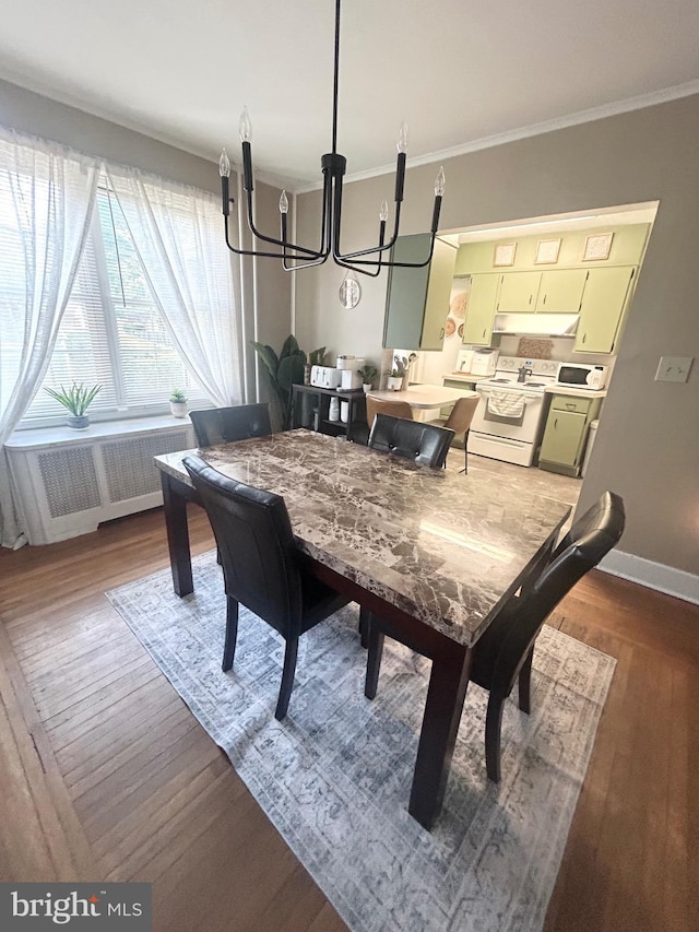 dining space with a chandelier, radiator, baseboards, wood finished floors, and ornamental molding