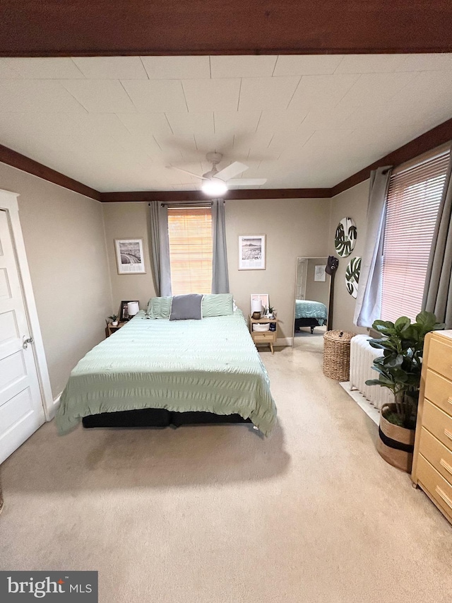 carpeted bedroom featuring crown molding, a ceiling fan, and radiator heating unit