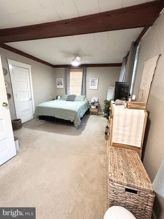 carpeted bedroom with ornamental molding, beamed ceiling, and a ceiling fan