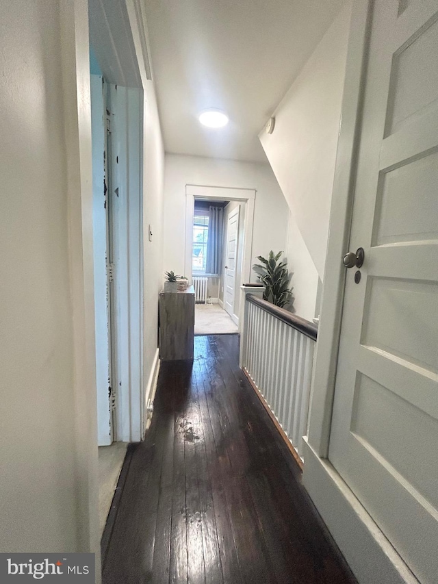 hallway with baseboards, radiator, and hardwood / wood-style floors