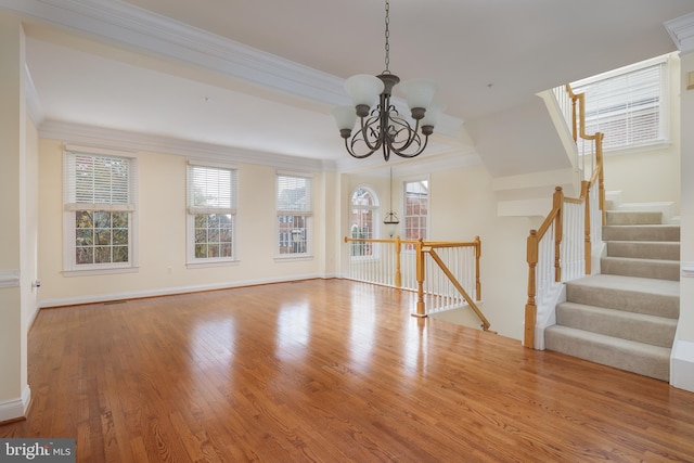 interior space featuring an inviting chandelier, ornamental molding, wood finished floors, baseboards, and stairway