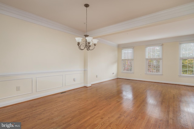 spare room featuring light wood-style floors, ornamental molding, a notable chandelier, and visible vents