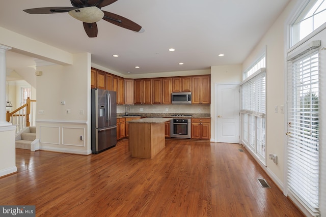 kitchen with a ceiling fan, visible vents, brown cabinets, stainless steel appliances, and dark wood-type flooring