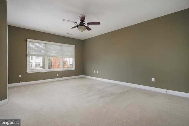 empty room with baseboards, visible vents, light carpet, and ceiling fan