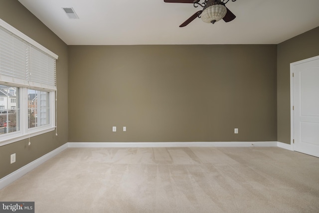unfurnished room with visible vents, a ceiling fan, baseboards, and light colored carpet