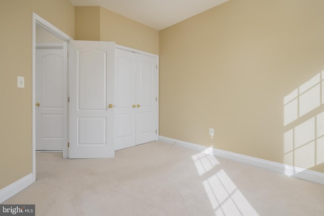 unfurnished bedroom with baseboards, carpet, and a closet