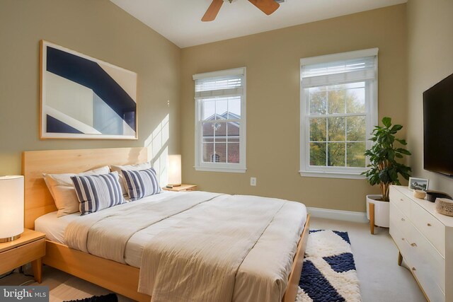 bedroom with baseboards, multiple windows, ceiling fan, and light carpet