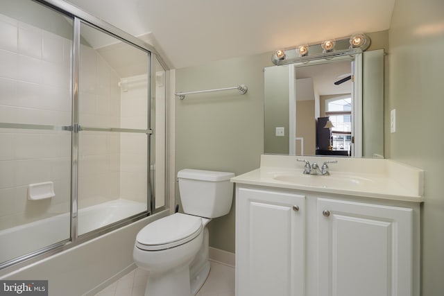 bathroom featuring vanity, tile patterned floors, baseboards, toilet, and enclosed tub / shower combo