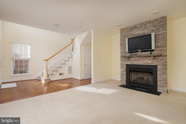 unfurnished living room with a fireplace, carpet floors, stairs, baseboards, and visible vents