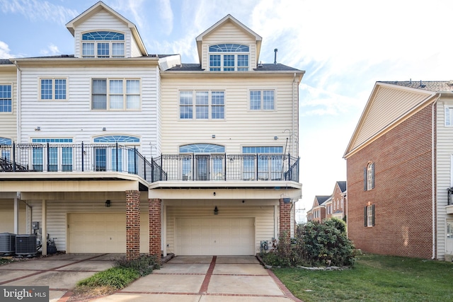 exterior space with concrete driveway, an attached garage, cooling unit, and a balcony