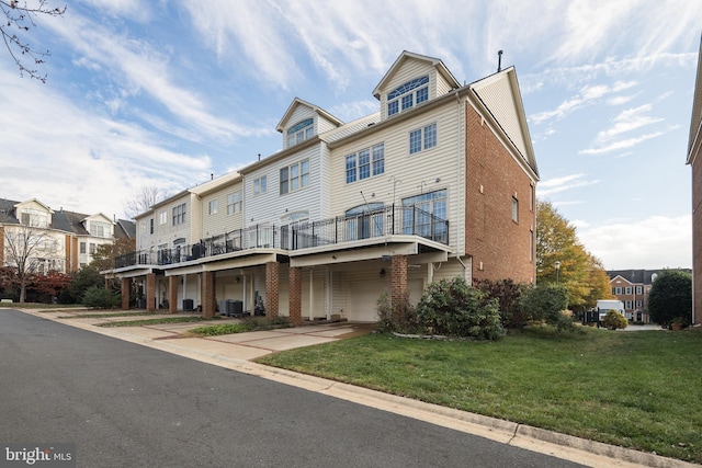 rear view of property featuring a lawn, central AC unit, a garage, brick siding, and concrete driveway
